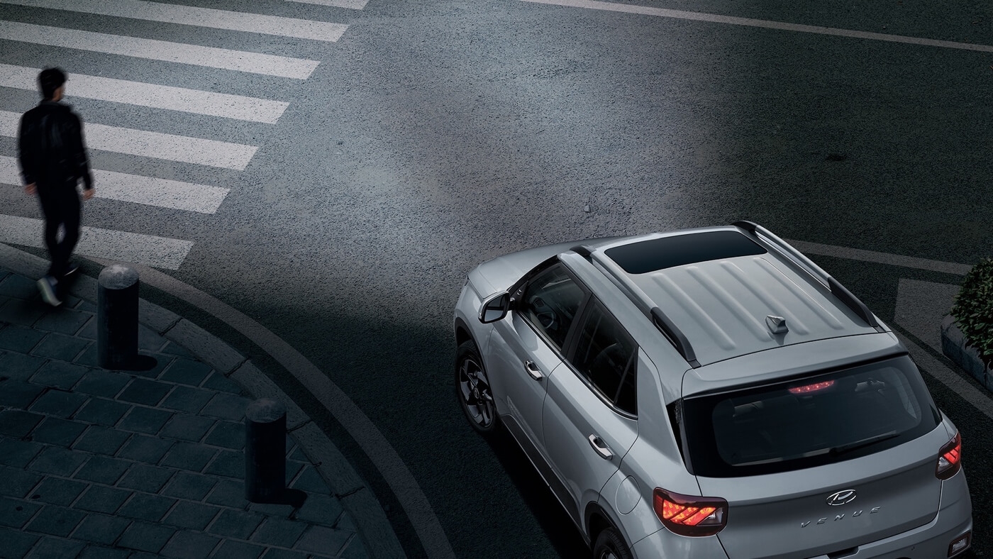 Le Hyundai Venue 2026 alerte en tout temps en laissant passer un piéton dans une rue.