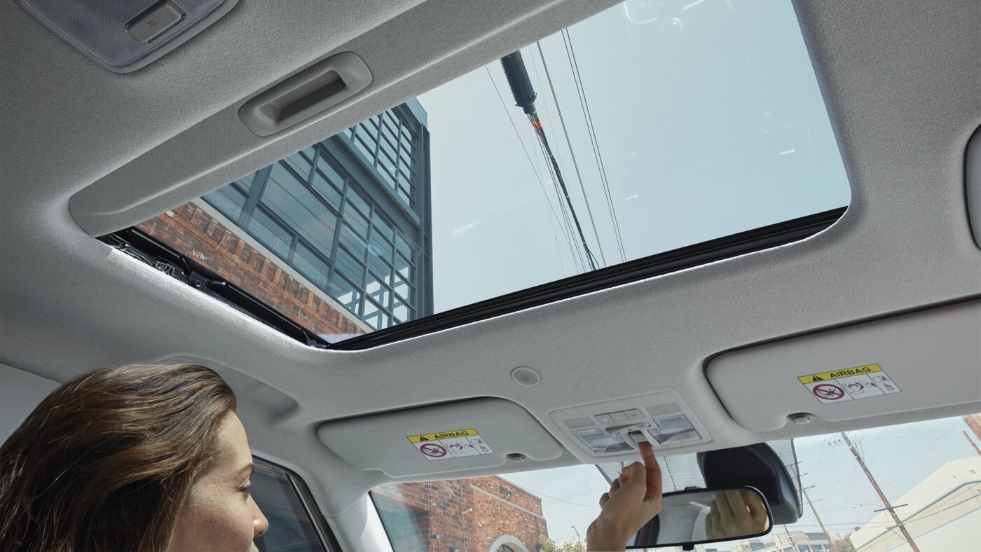 Femme au volant du Hyundai Venue 2026 ajustant le toit ouvrant électrique.