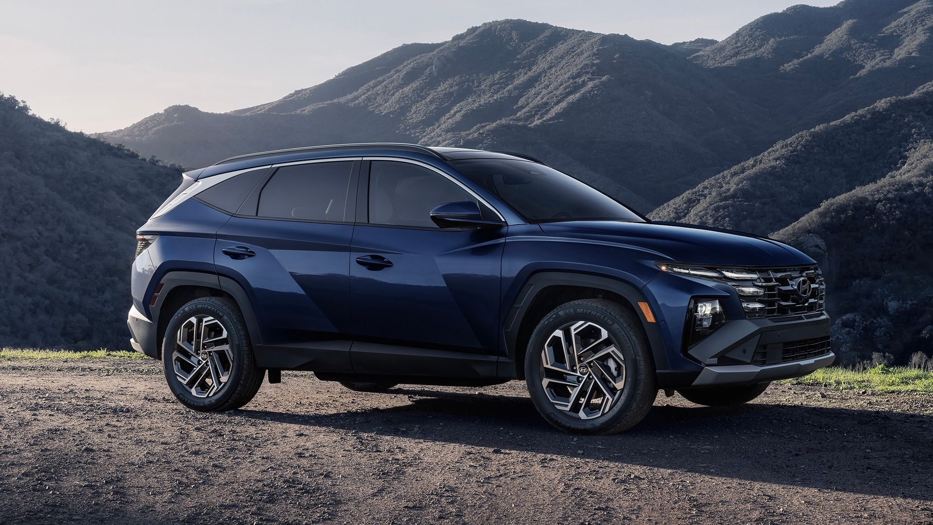 Le Hyundai Tucson Hybride 2025 stationné sur la gravel avec un décor de montagne en arrière.